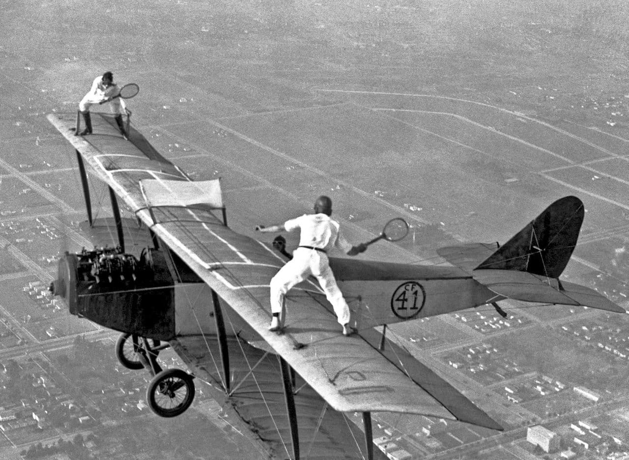 Two men are playing tennis on a plane.